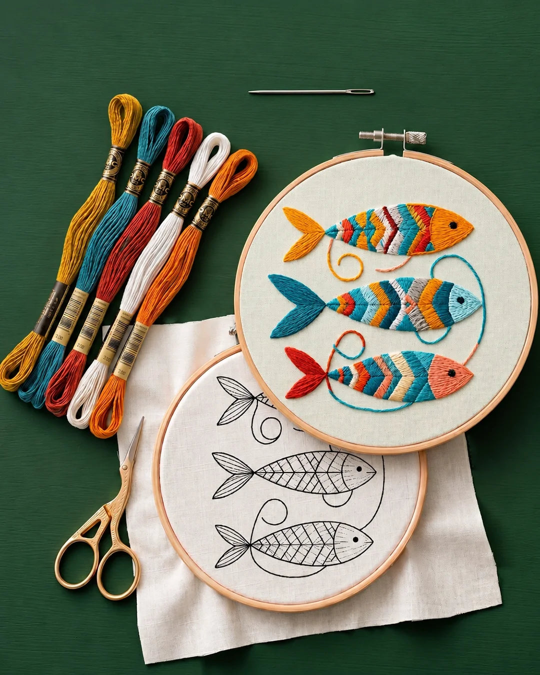 Embroidery hoop with colorful fish design, threads, scissors, and a needle on a green background