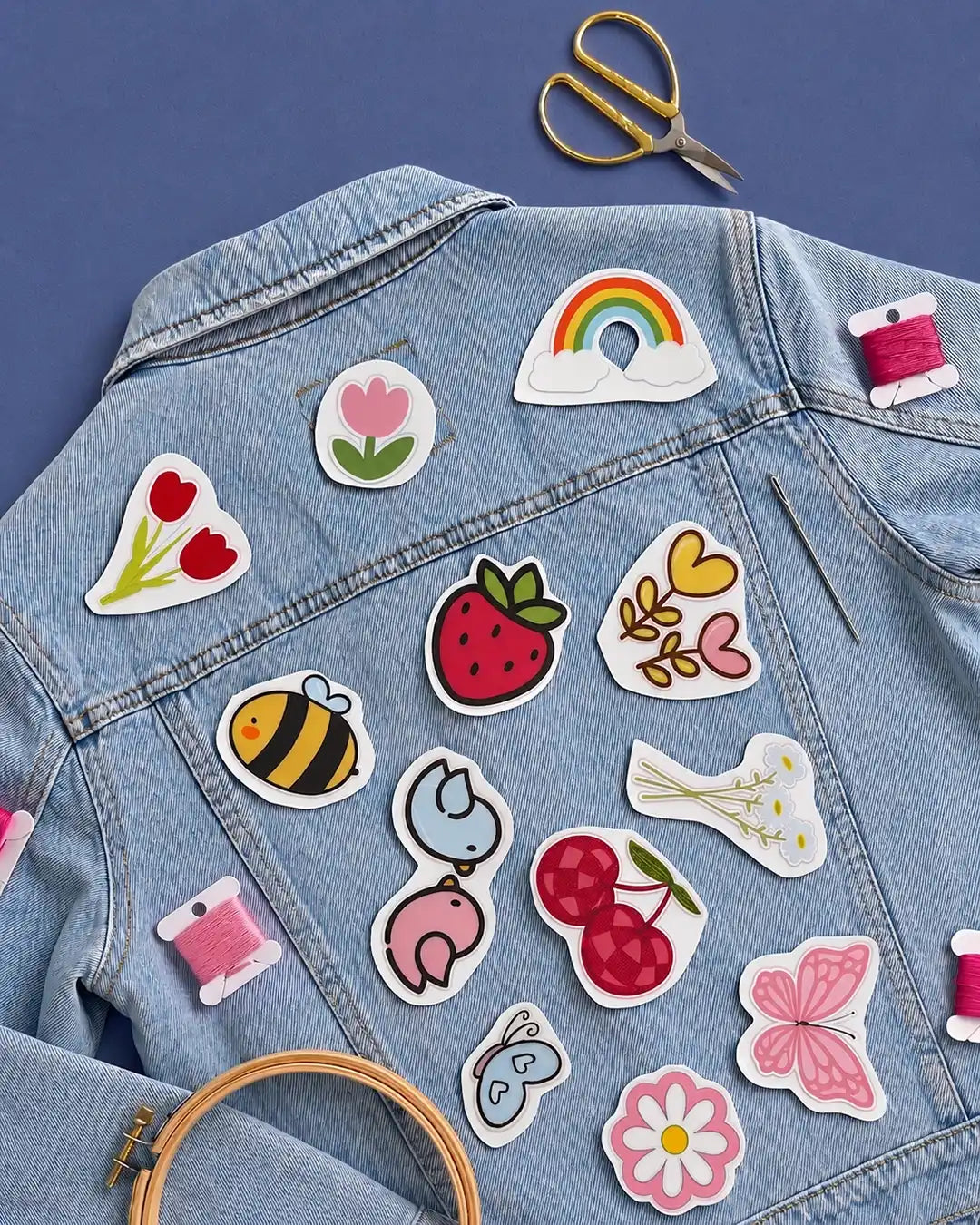 Denim jacket with various colorful water soluble stick and stitch stickers including flowers, a bee, and a rainbow.
