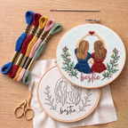 Embroidery hoop with 'bestie' design, embroidery threads, and scissors on a wooden surface