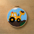 Embroidery hoop with a punch needled yellow bulldozer design on a wooden surface