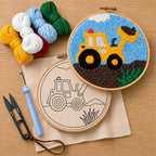 Embroidery hoops with construction-themed designs with a punch needled buldozer, punch needle, thread cutter and yarns on a wooden surface