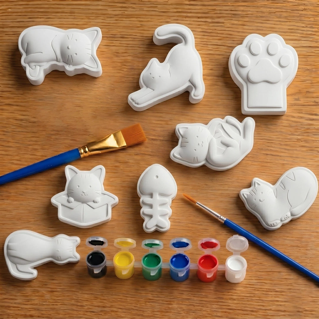 White ceramic animal concrete  shapes on a wooden surface with paintbrushes and paint.