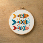 Embroidery hoop with colorful fish design on a wooden surface