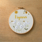 Embroidery hoop with floral design and 'Riyana' text(custom name) on a wooden surface