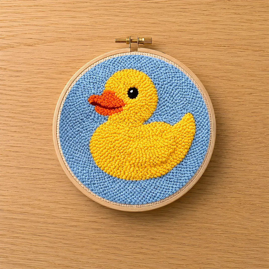 Embroidery hoop with a yellow duck on a blue background on a wooden surface