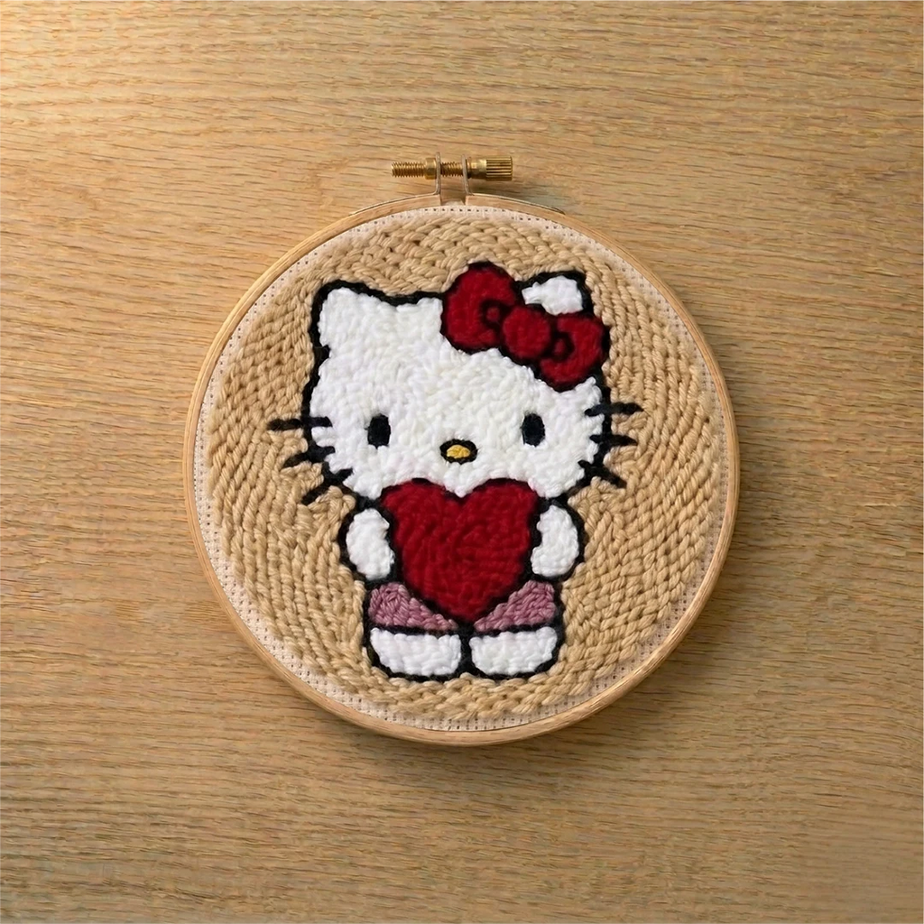Embroidery hoop with a punch needled kitty character holding a heart on a wooden surface