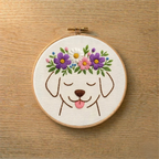 Embroidery hoop with a dog face design and floral crown on a wooden surface
