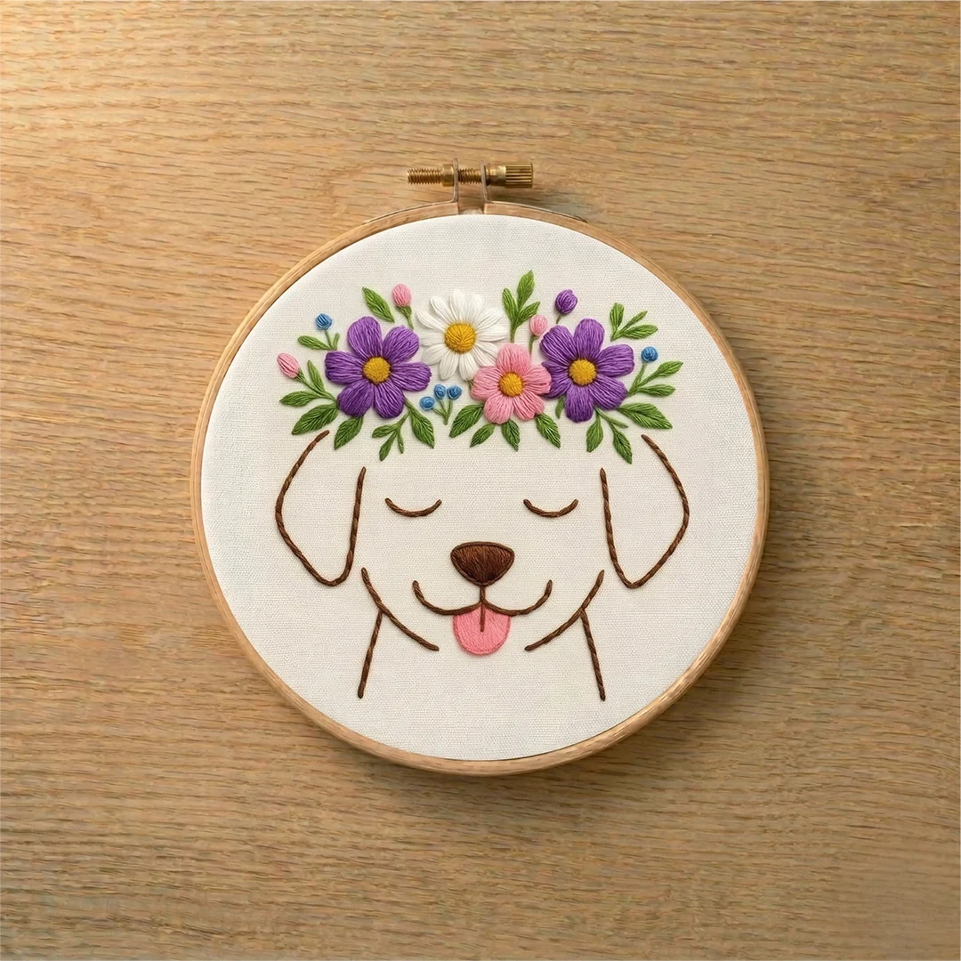 Embroidery hoop with a dog face design and floral crown on a wooden surface