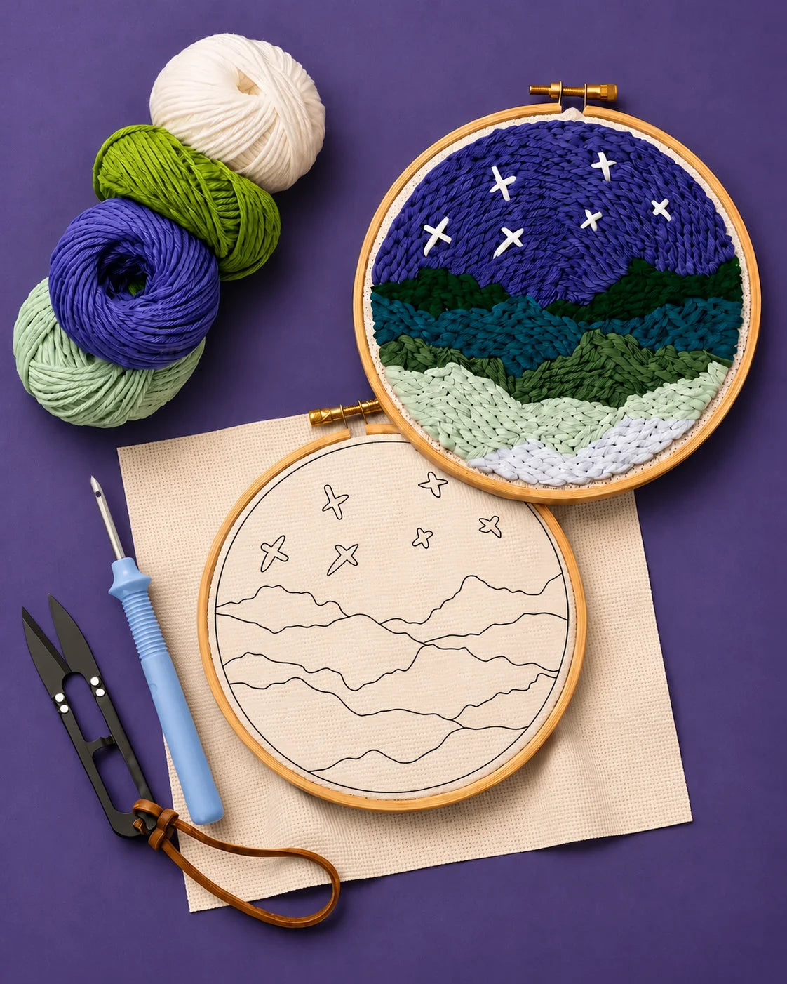 Embroidery hoops with mountain and star design, yarn balls, and sewing tools on a purple background
