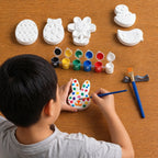 Child painting a concrete rabbit with various concrete shapes and paint colors on a wooden table.