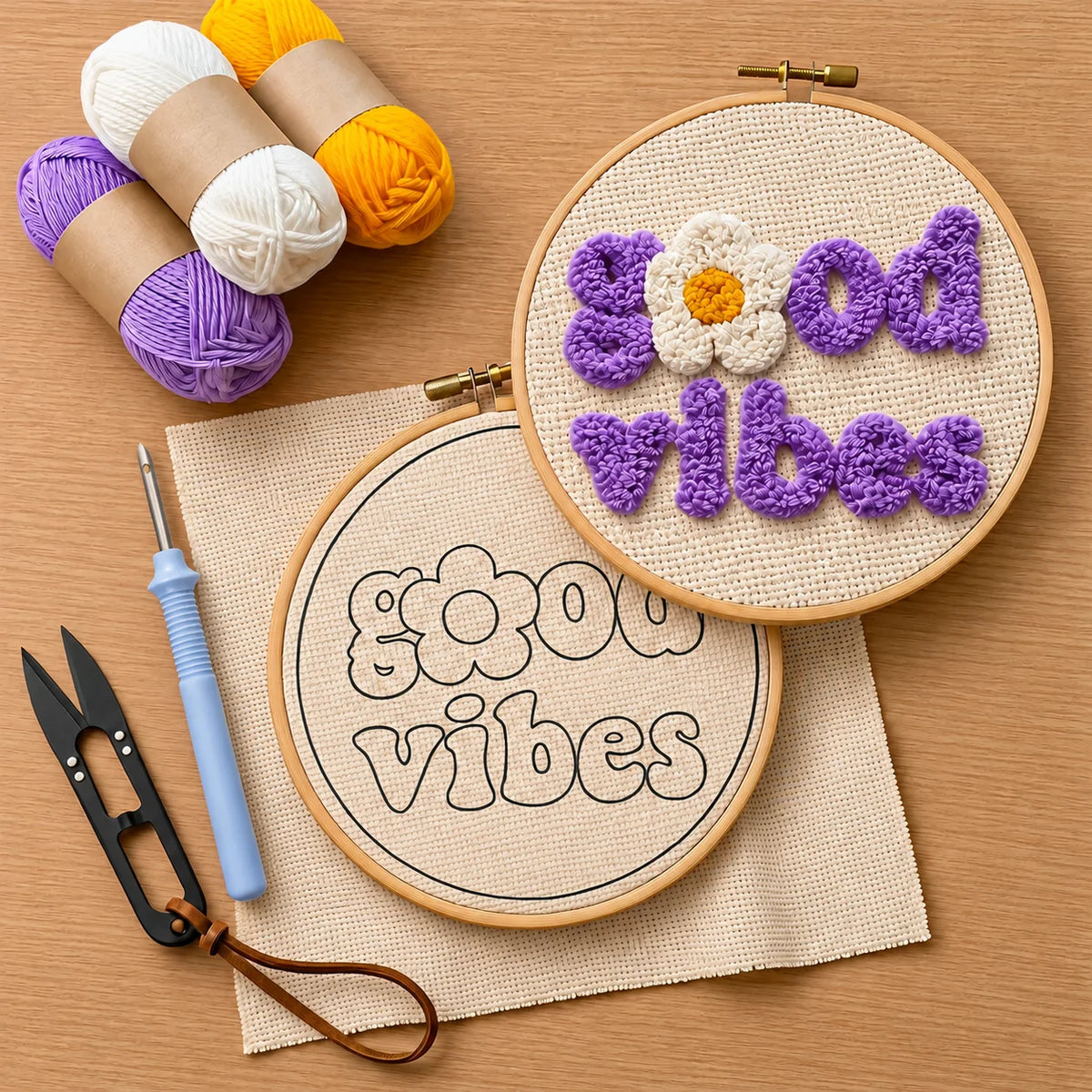 Embroidery hoops with 'good vibes' text and, punch needle, thread cutter, yarn on a wooden surface