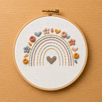 Embroidery hoop with a rainbow and heart design on a wooden surface
