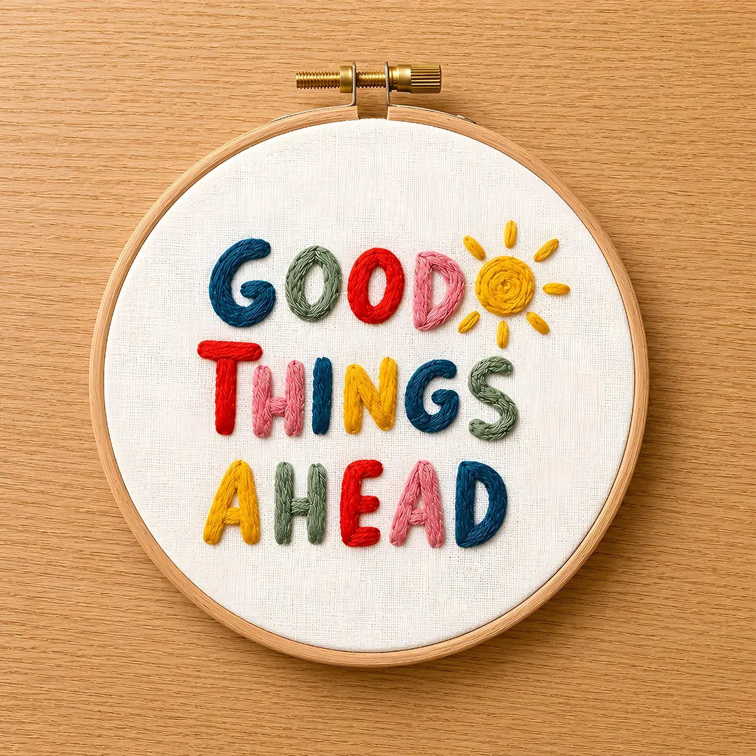 Embroidery hoop with 'Good Things Ahead' text and sun design on a wooden surface