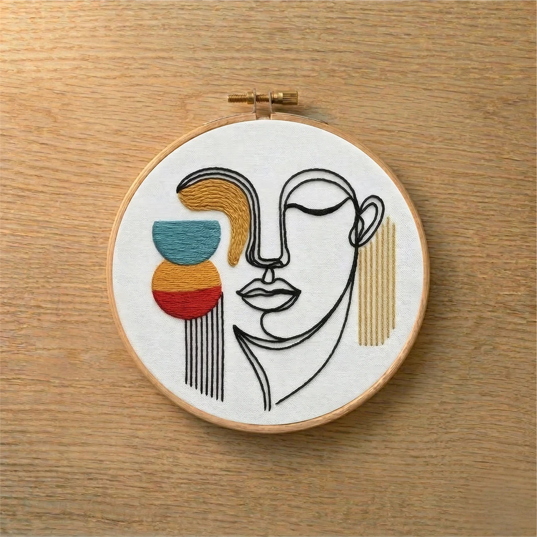 Embroidery hoop with abstract face design on a wooden surface