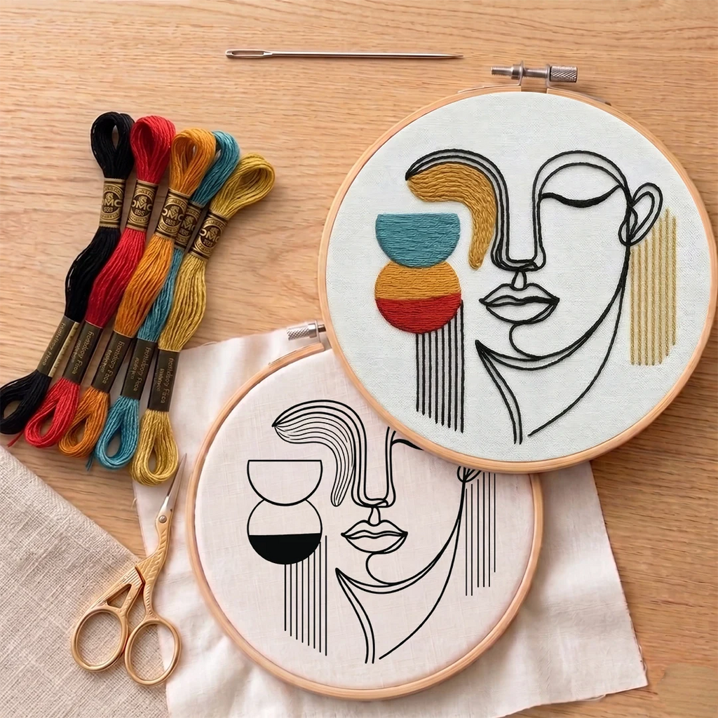 Embroidery hoops with face designs and colorful thread on a wooden surface