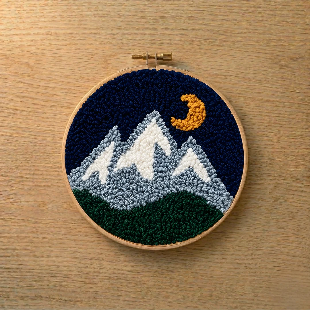 Embroidery hoop with mountain and moon design on a wooden surface