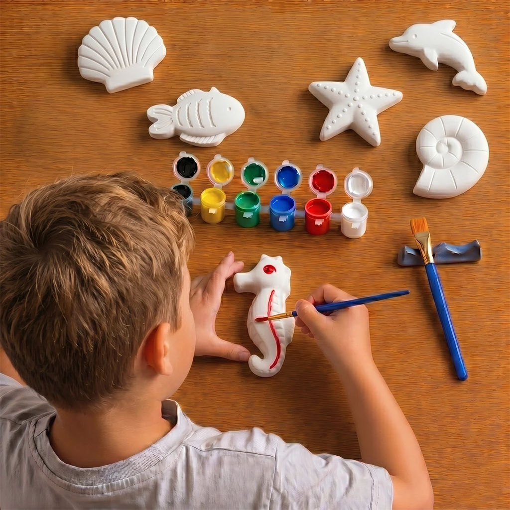 Child painting a seahorse-shaped concrete object with various colors on a wooden table.