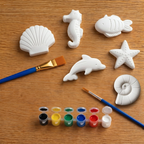 Set of white concrete  sea creature molds on a wooden surface with paintbrushes and paint.