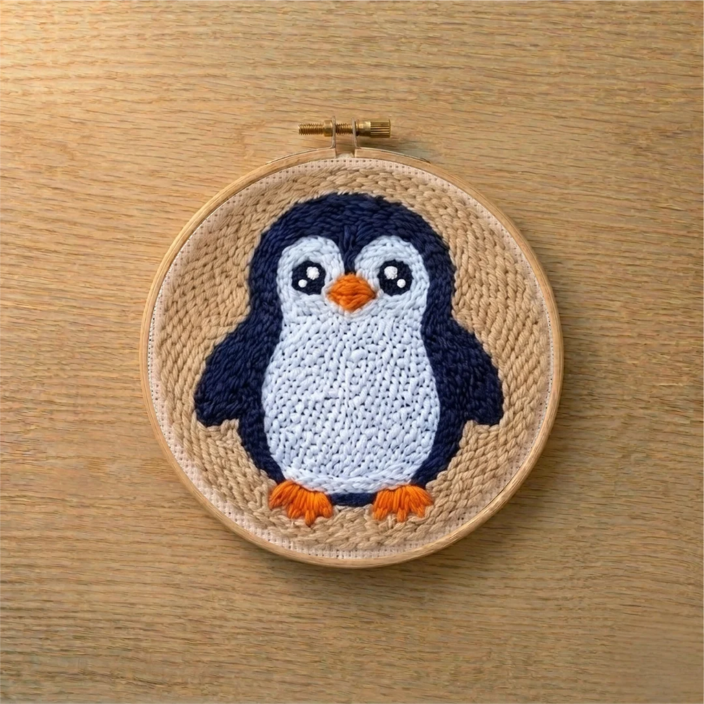 Punch needled penguin in a wooden hoop on a wooden surface