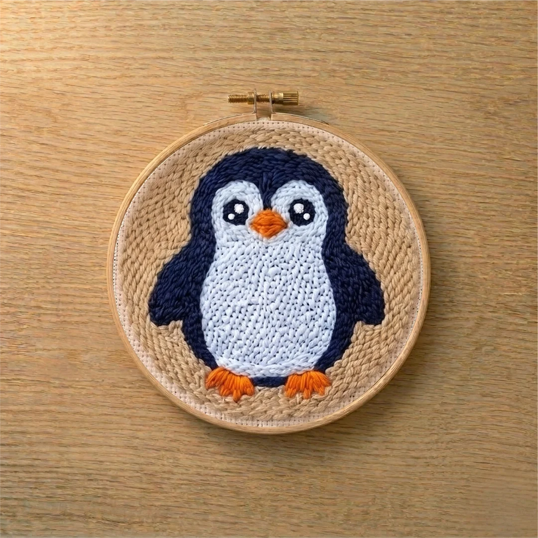 Punch needled penguin in a wooden hoop on a wooden surface