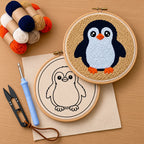 Embroidery hoops with penguin punch needle designs and yarn on a wooden surface