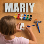 Child painting a letter 'A' with colorful paint bottles and brushes on a wooden surface.