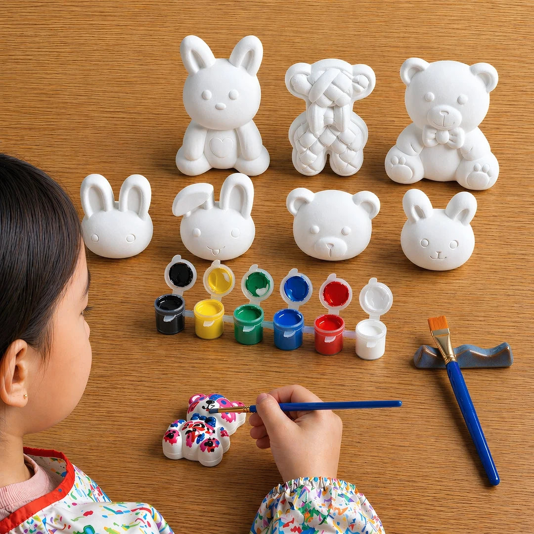 Child painting concrete  animal figurines on a wooden table with paint supplies.