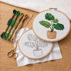 Embroidery hoops with plant designs and embroidery threads on a wooden surface