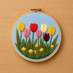 Embroidery hoop with colorful tulip design on a wooden surface