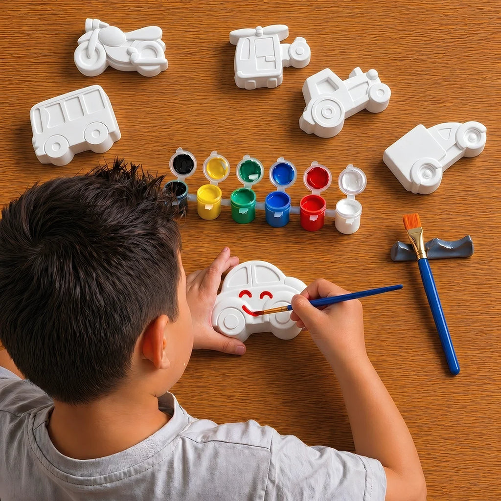 Child painting a toy car with various paint colors and tools on a wooden table.