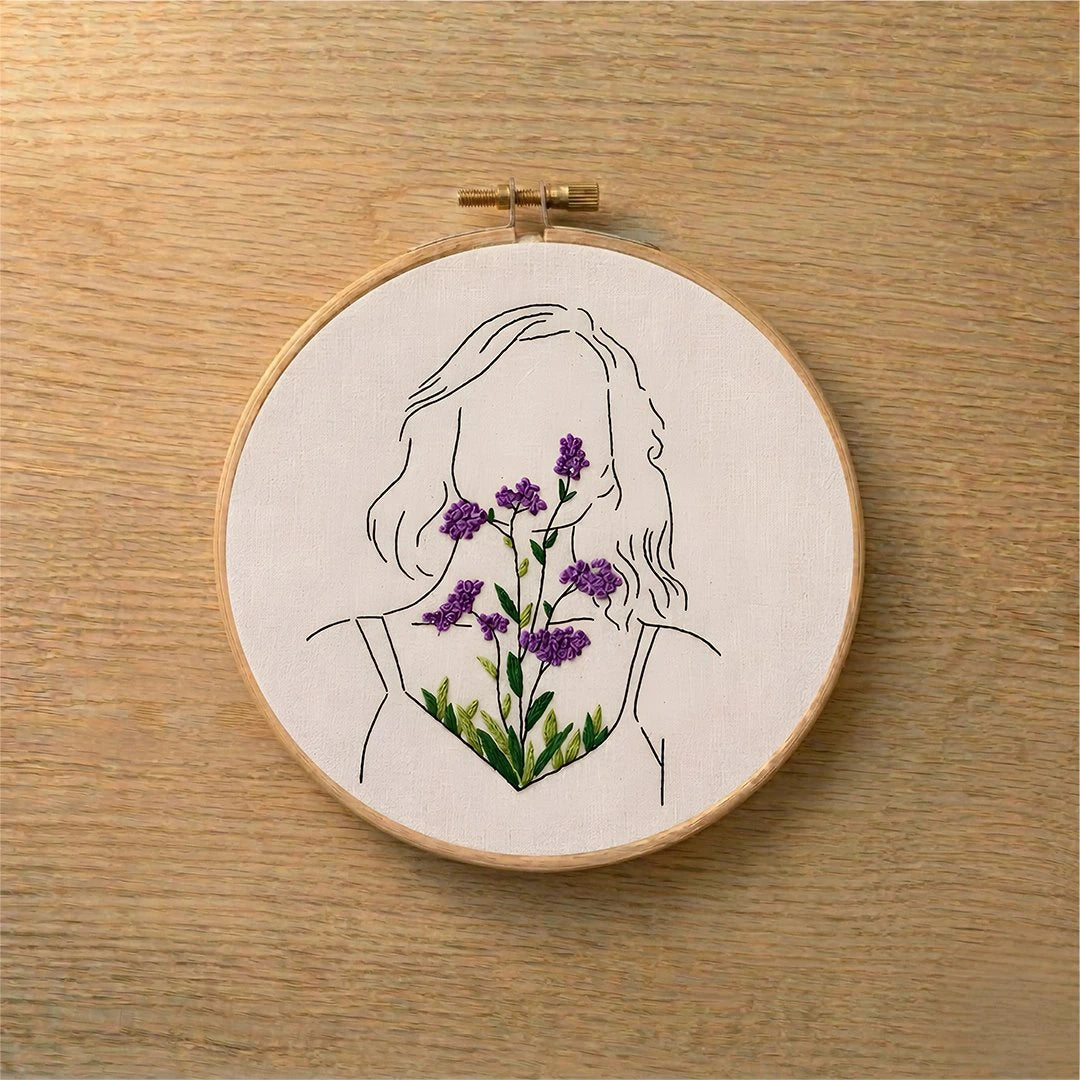 Embroidery hoop with a silhouette of a woman holding flowers on a wooden surface